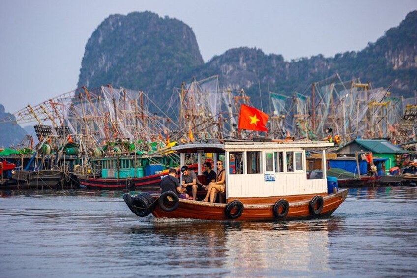 A boat with a Vietnamese flag, surrounded by fishing boats and nets, with a mountainous landscape in the background. 1