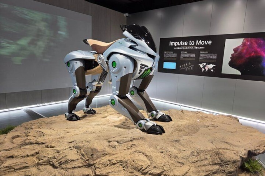 A humanoid robot with green accents on its legs and a display titled 'Impulse to Move' in the background. 2
