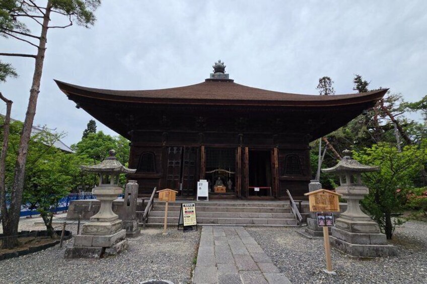 A traditional Japanese temple with a large curved roof, stone lanterns, and a stone staircase leading to the entrance. 5