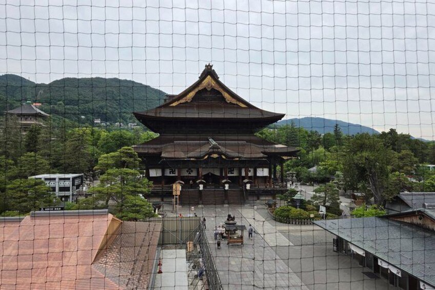 A traditional Japanese temple with a large, ornate roof, surrounded by lush greenery and hills. 3