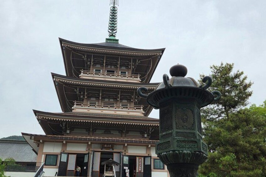 A traditional Japanese pagoda with multiple tiers, a green lantern, and a mountain in the background. 2
