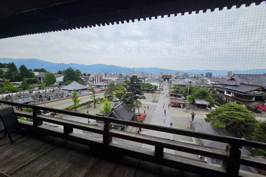 A traditional Japanese town with wooden buildings, a central plaza, and mountains in the background. 4