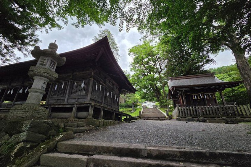 A traditional Japanese building with a wooden structure, stone lantern, and a stone pathway leading to it. 3