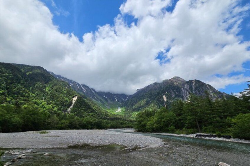 A river flowing through a mountainous valley with dense forest and rocky terrain. 2