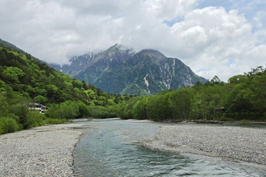 A river flowing through a mountainous landscape with dense greenery and a prominent mountain in the background. 4