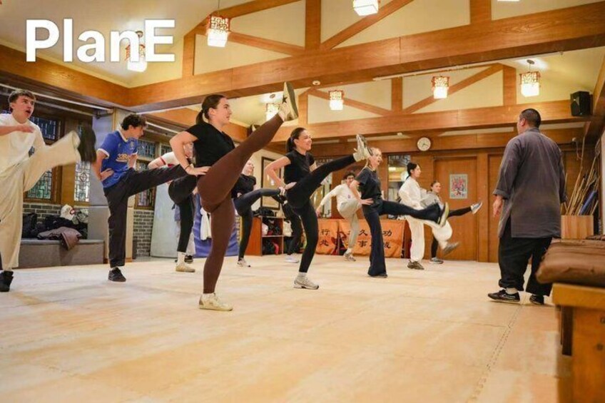A group of people practicing martial arts in a wooden room with a high ceiling. 3