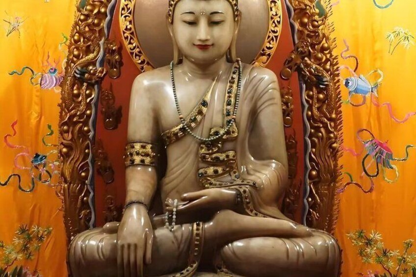 A seated statue with intricate gold detailing and a colorful backdrop. 5
