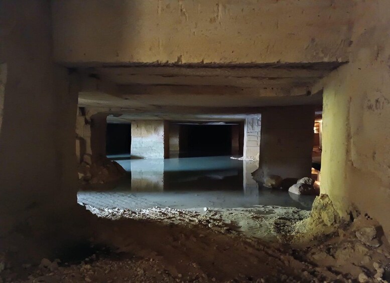 An underground passageway with concrete pillars and a reflective floor. 2