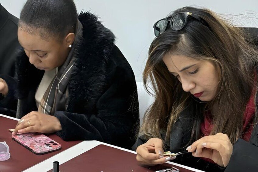 Two individuals seated at a table with a smartphone and a pen. 3