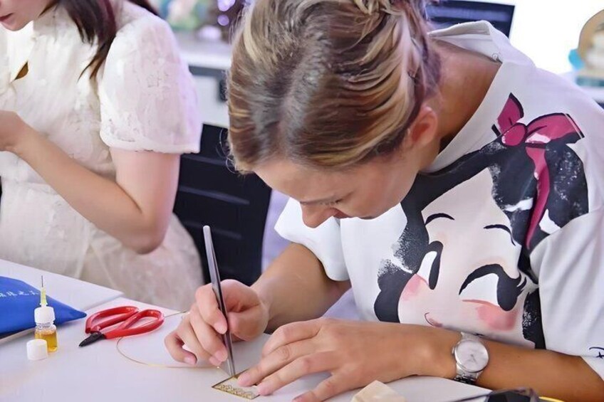 A person writing on a piece of paper with a pen, a blue folder, and red-handled scissors on the table. 4