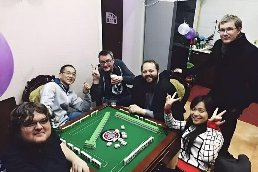 A group of people around a snooker table with a green felt surface, a white cue, and red and black balls. 2