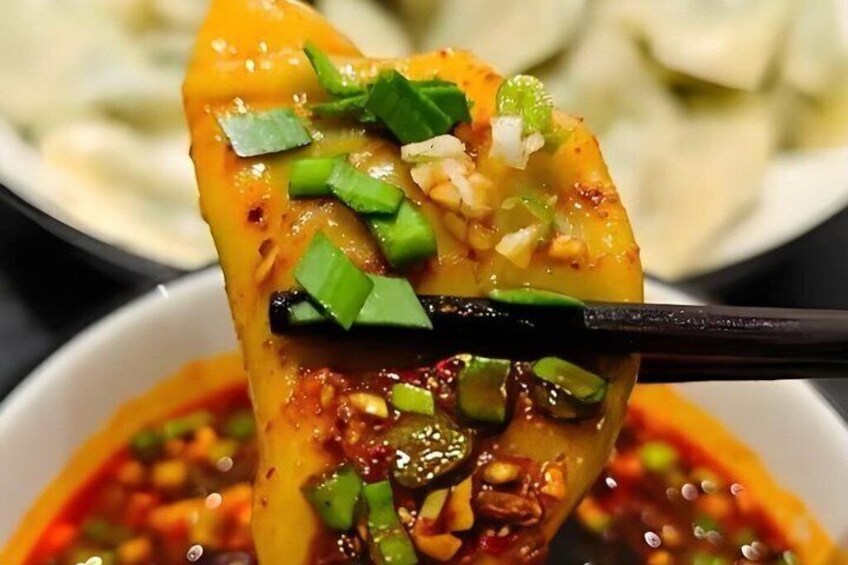 A close-up of a food item being held with chopsticks, garnished with green onions and sesame seeds. 5