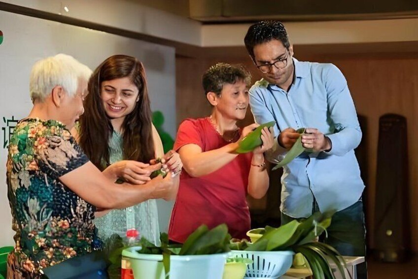 Four people engaged in a cooking activity with green leaves and a bowl. 5