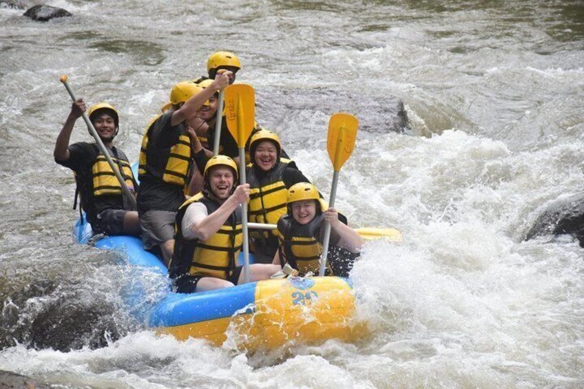 A group of people in a blue raft navigating a river with rapids. 2