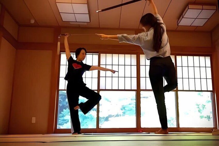 Two people practicing martial arts in a room with large windows. 4