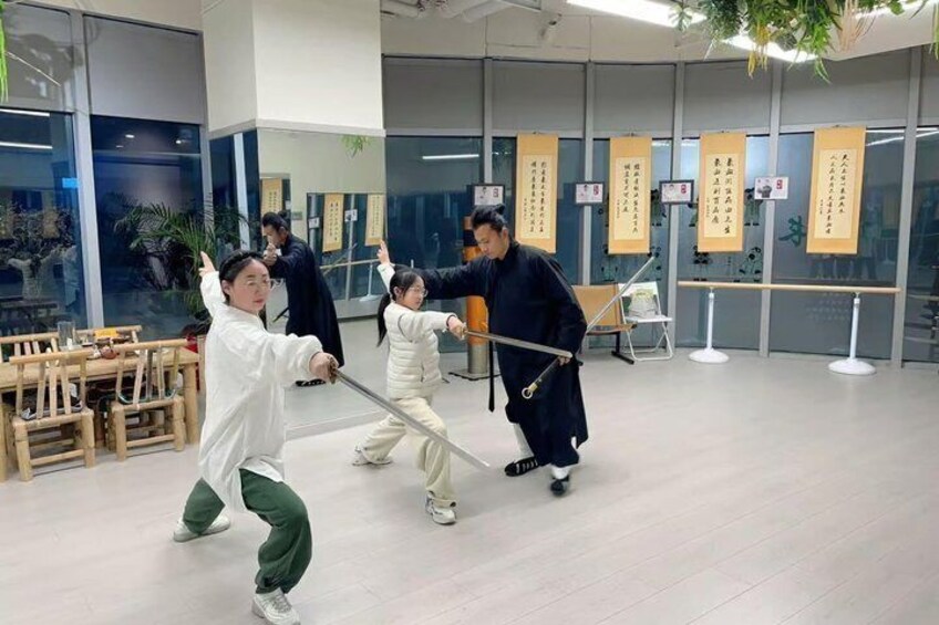 A martial arts class with students practicing with swords in a modern training room. 3