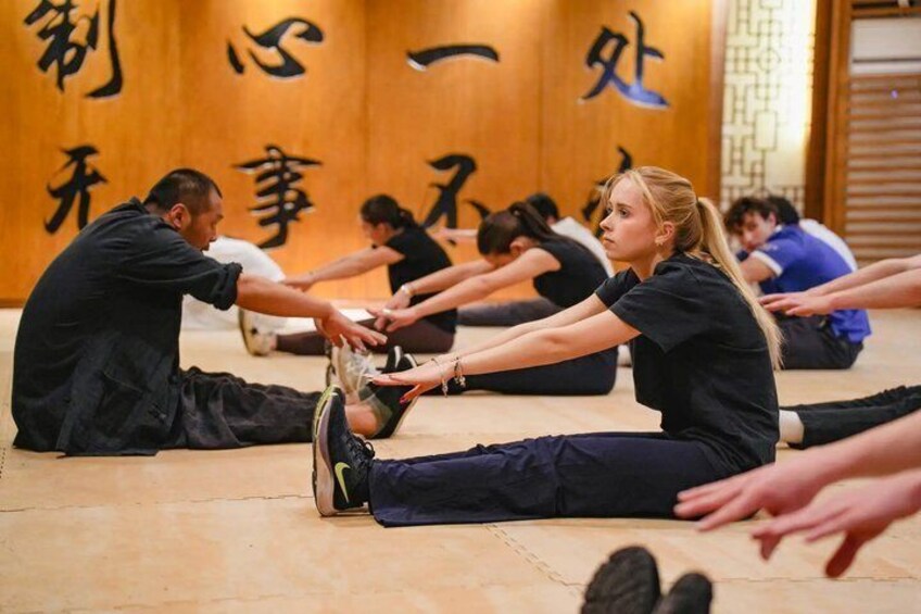 A group of people stretching on the floor in a room with wooden walls and Japanese characters. 5