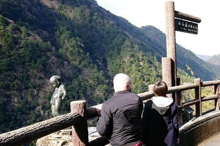A wooden viewing platform with a statue and a signpost. 4