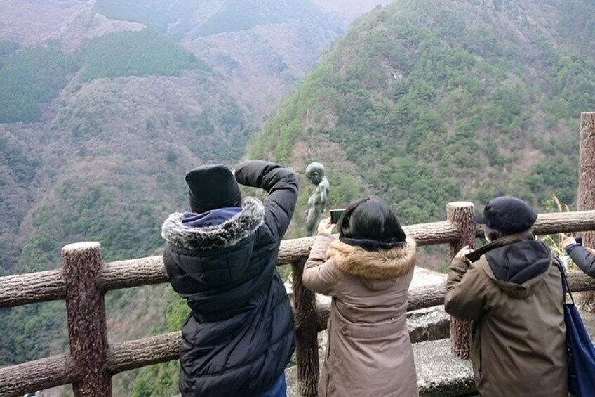 People taking photos of a statue on a mountain trail. 5