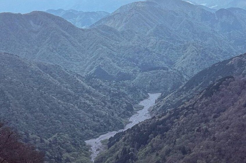 A river winding through a mountainous valley with dense forest coverage. 2