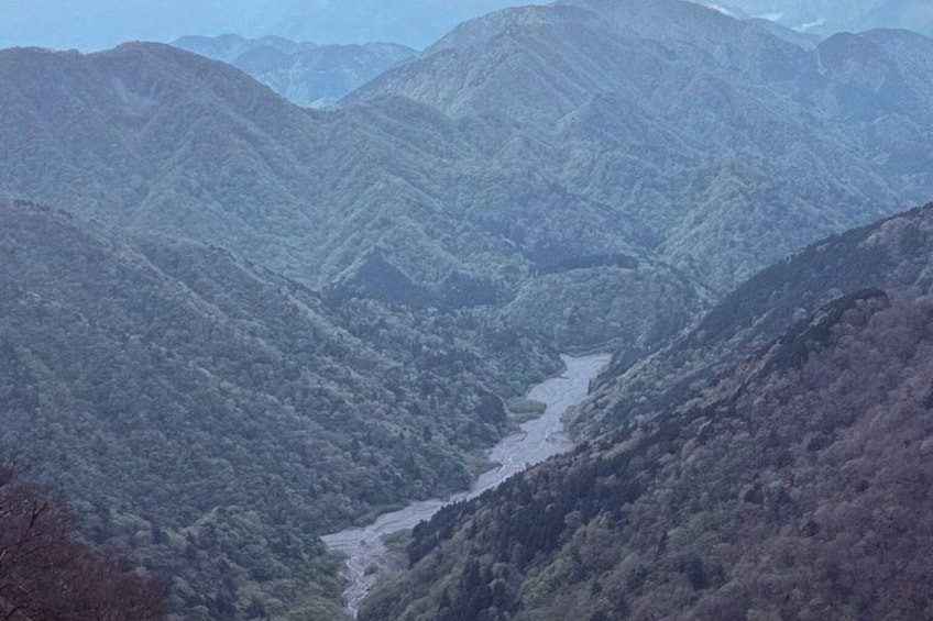 A valley with a river, surrounded by forested mountains. 4