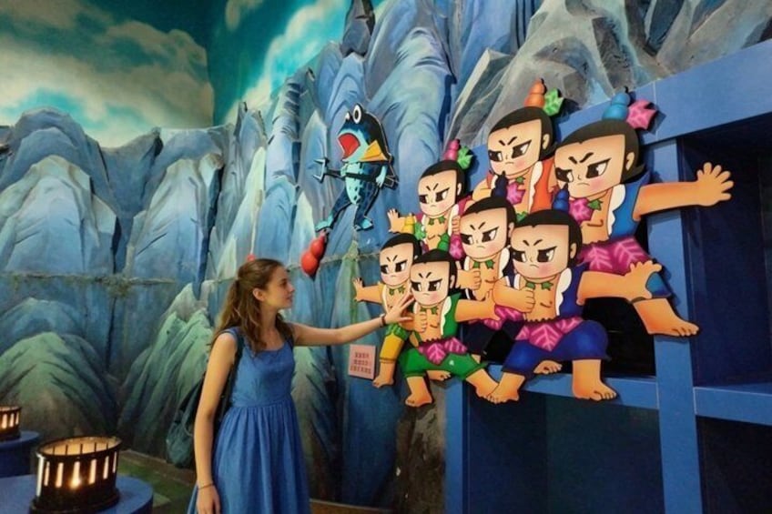 A person interacting with a wall of cartoon characters in a mountainous setting. 1