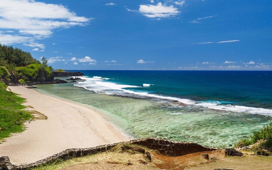 A beach with clear turquoise waters, a sandy shore, and lush greenery. 5