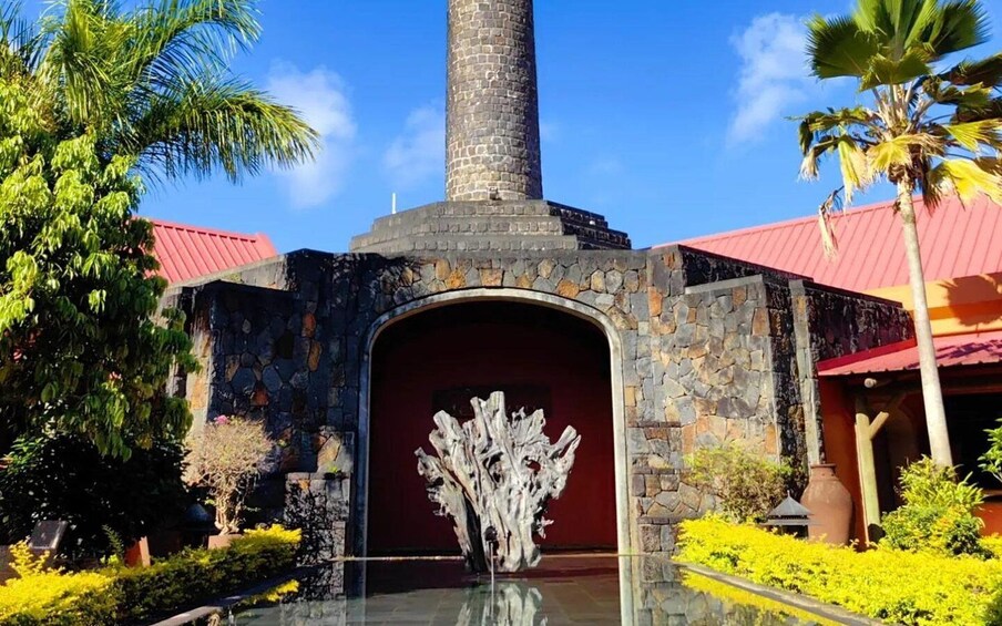 A stone building with a red roof, a tall chimney, and a decorative entrance. 1
