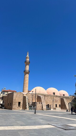A mosque with a tall minaret and three dome-shaped structures. 4