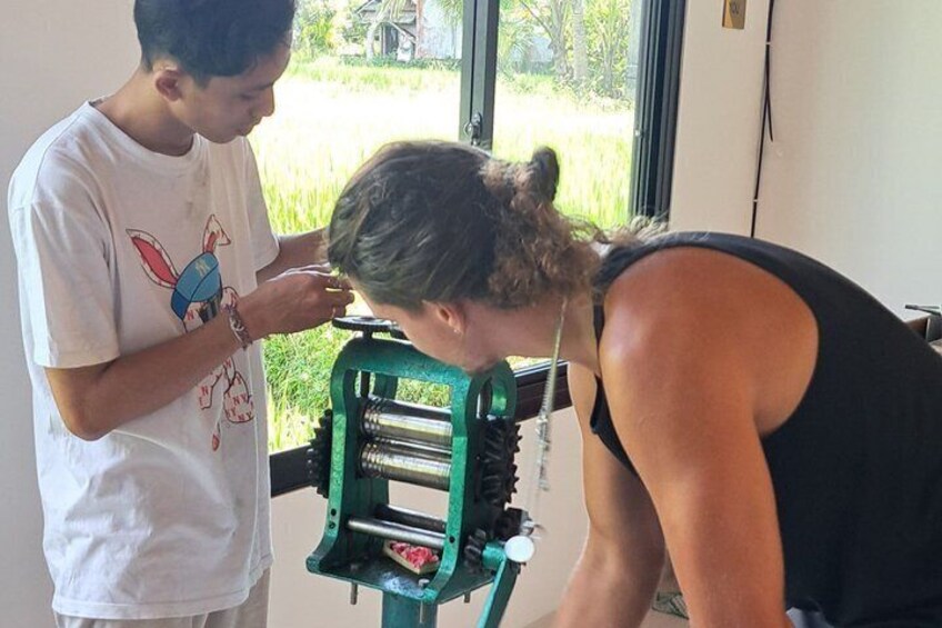 Dos personas usando un equipo verde, posiblemente para preparar alimentos, en una habitación con ventana. 5