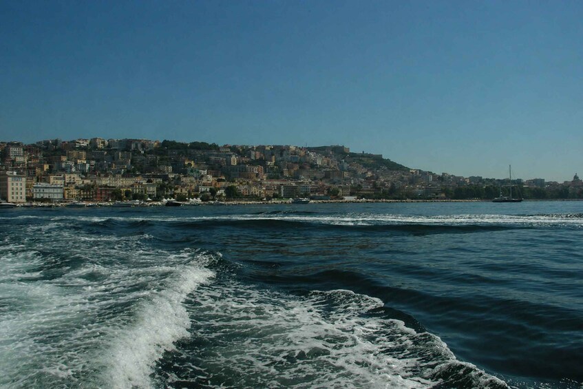A coastal cityscape with buildings along the waterfront and waves in the foreground. 4