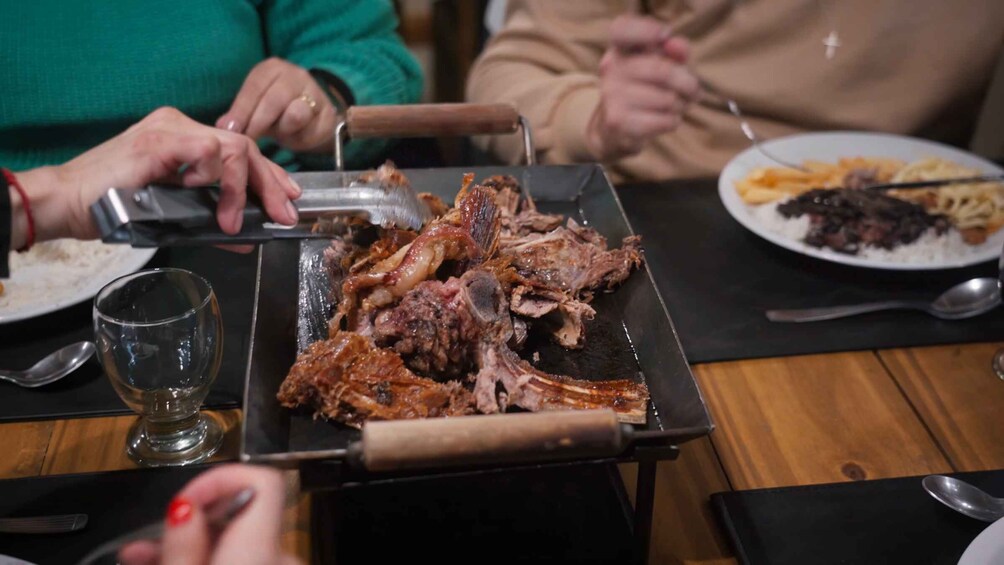 A person carving meat on a grill. 4