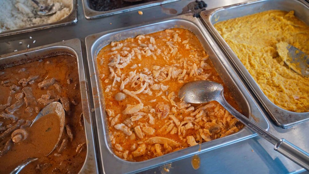 A buffet with various dishes including a creamy soup, a chicken dish with sauce, and a yellow rice dish. 2