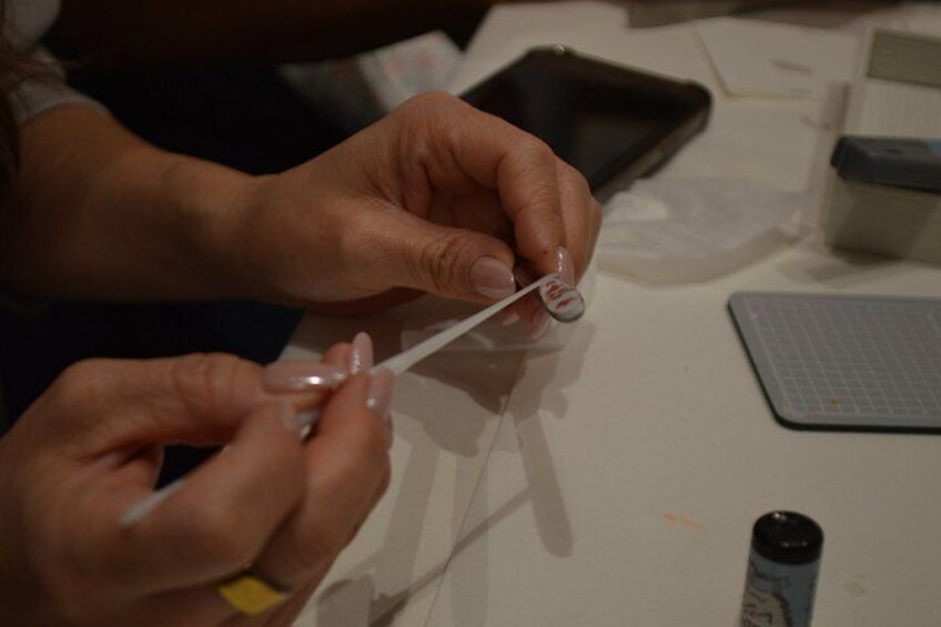 Hands holding a transparent object, possibly a tool or component, with a grid-patterned surface in the background. 4