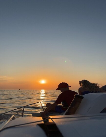 A sunset over the ocean with a boat and two people on deck. 2