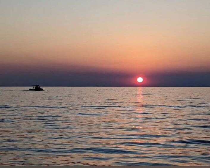 A sunset over a calm sea with a boat in the distance. 5