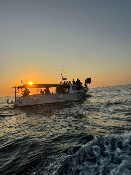 A boat with people on board sailing on the water during sunset. 1