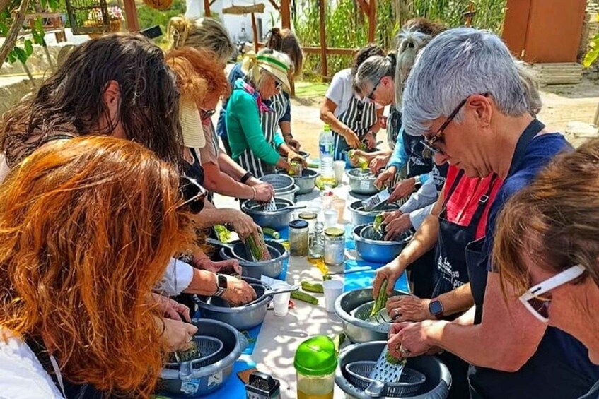 A group of people engaged in a communal food preparation activity outdoors. 2