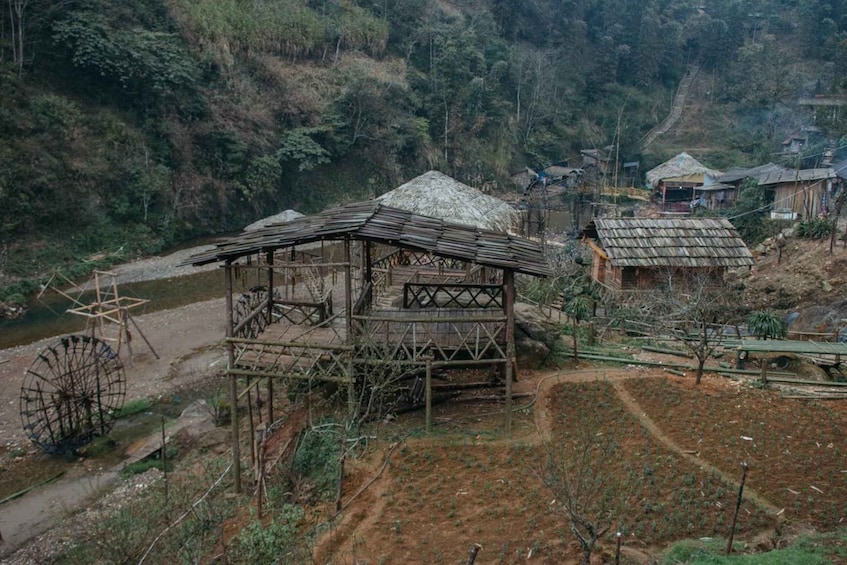 A rural village with traditional wooden structures, a water wheel, and terraced fields. 5