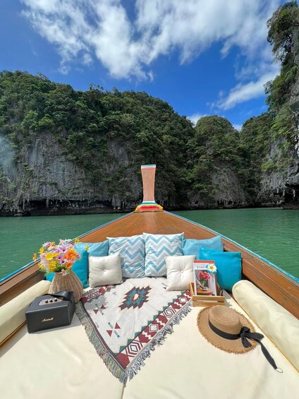 A boat with a colorful cushion, a woven basket with flowers, a patterned rug, and a hat on the deck. 1