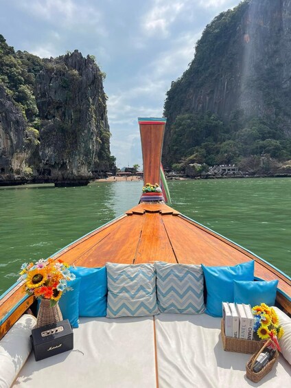 A boat with a wooden deck, cushions, a vase of sunflowers, a Marshall amplifier, and a basket of books and flowers. 2