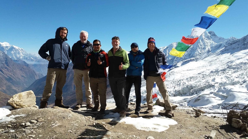 A group of people standing on a snowy mountain peak with flags. 2