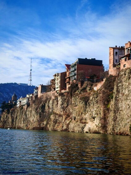 A river with buildings on a cliff, a tower, and a mountain in the background. 2