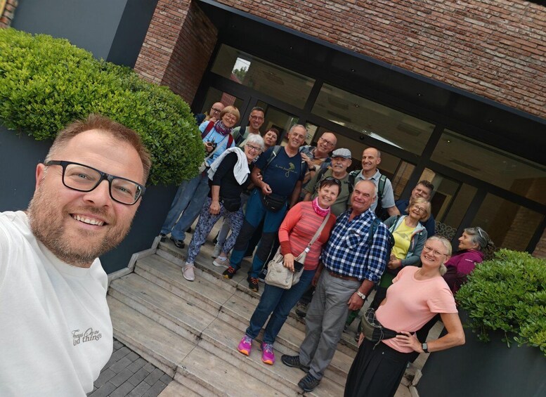A group of people standing on a staircase outside a building with brick walls and glass doors. 1