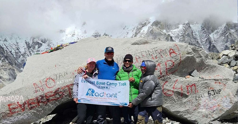 A group of people standing on a mountain with a banner reading 'Everest Base Camp Trek.' 1