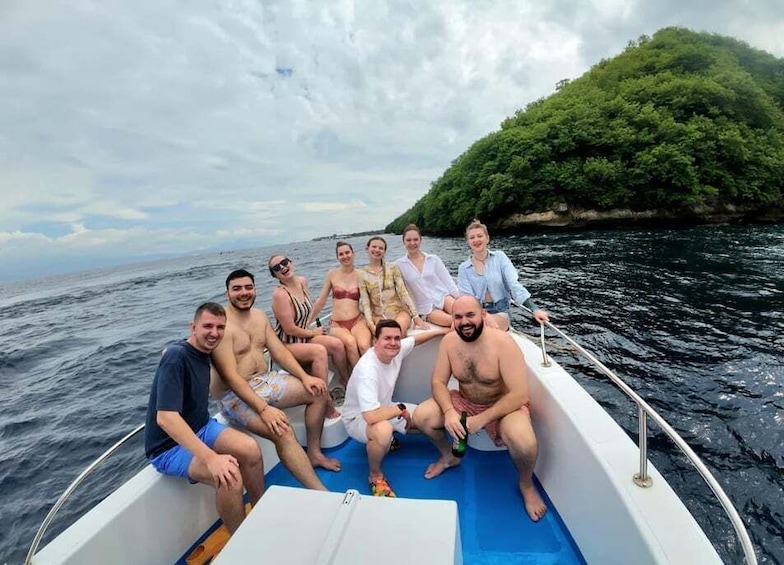 Un grupo de personas en un barco, con una isla boscosa al fondo. 1