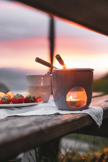 A candlelit mug on a wooden table with strawberries and a candle in the background. 1