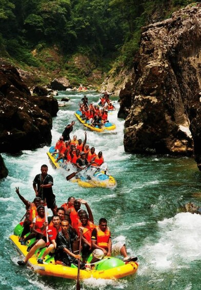 People rafting down a river surrounded by rocky cliffs. 5