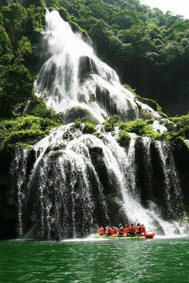 A multi-tiered waterfall with a group of people in a raft at the base. 3