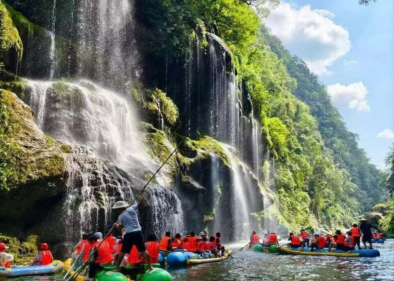 People rafting down a river with a waterfall in the background. 1
